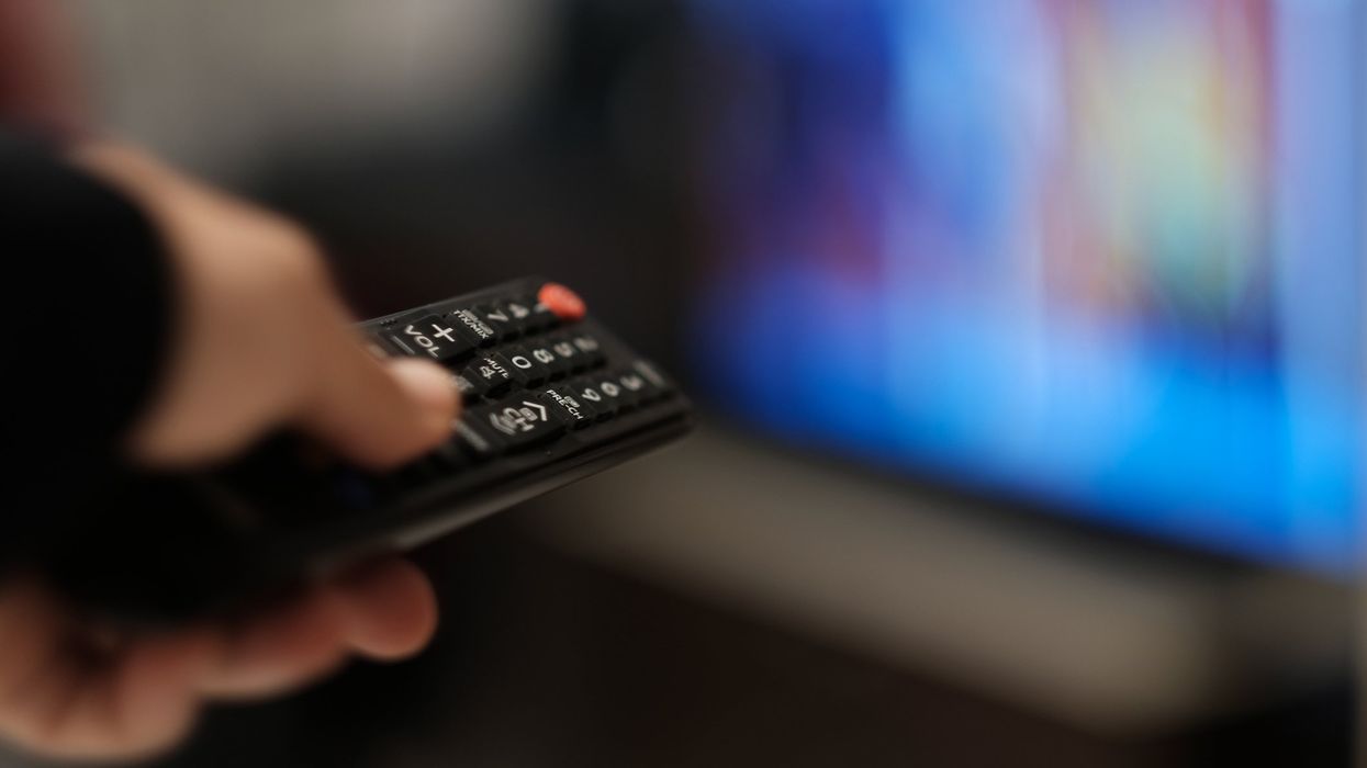 Remote control in hand to change channels.