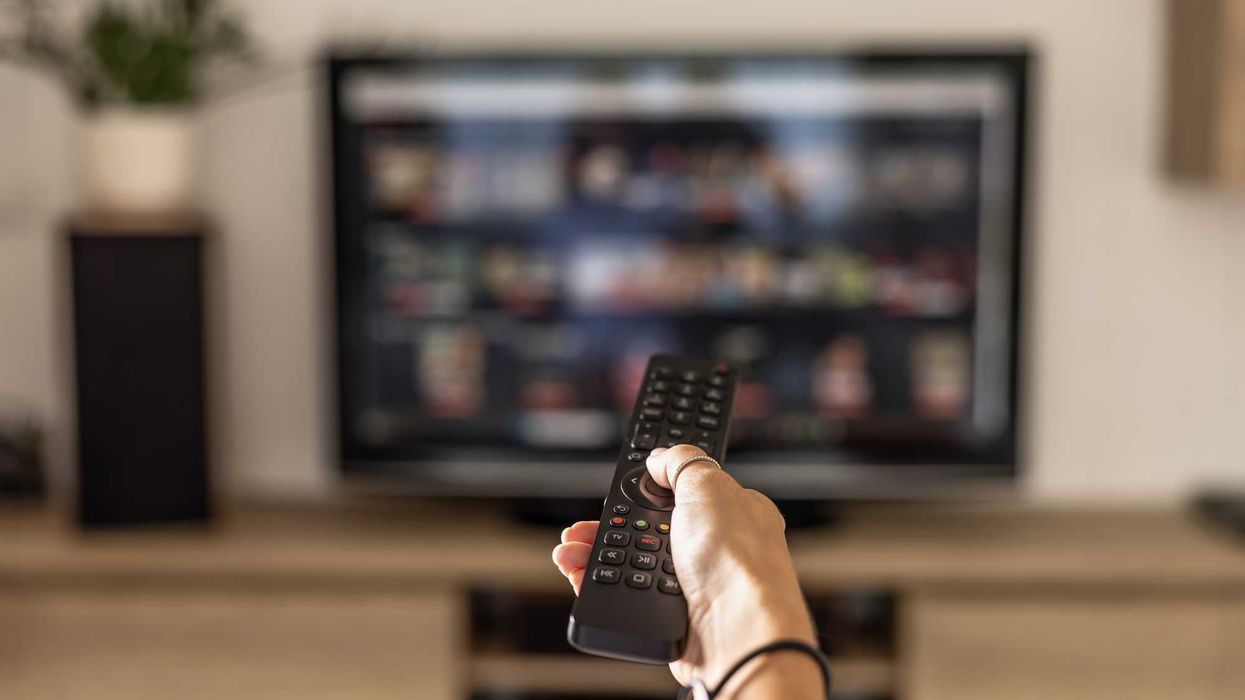 Someone holding a remote, pointing it to a TV.