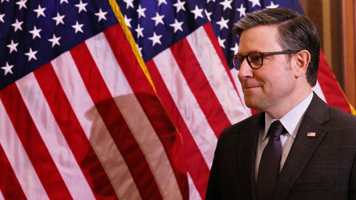 Speaker Mike Johnson standing in front of American flags