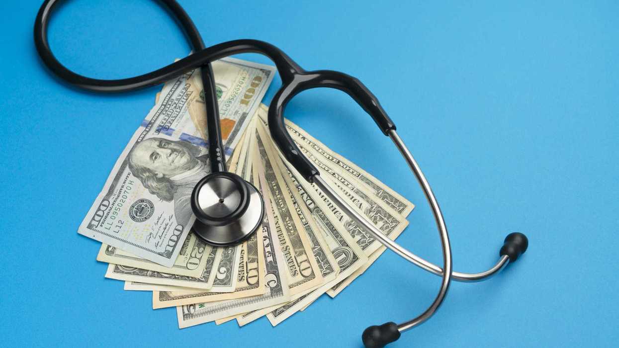 stethoscope and us dollar bills on blue-colored background.