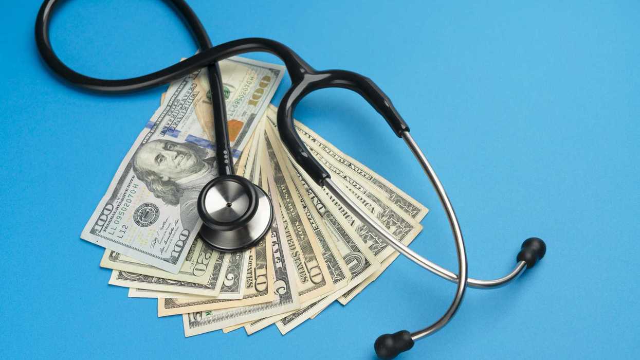 stethoscope and us dollar bills on blue-colored background.