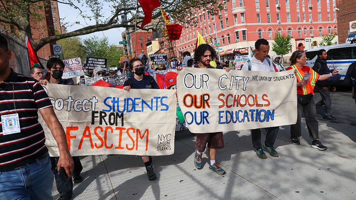 Student protestors marching, holding signs that read, "Protect students from fascism" and "Our city, our schools, our education."