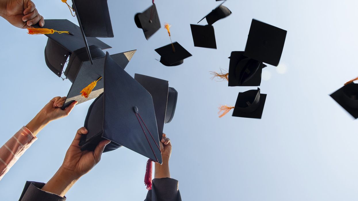 Students holding graduation caps. Students graduating.