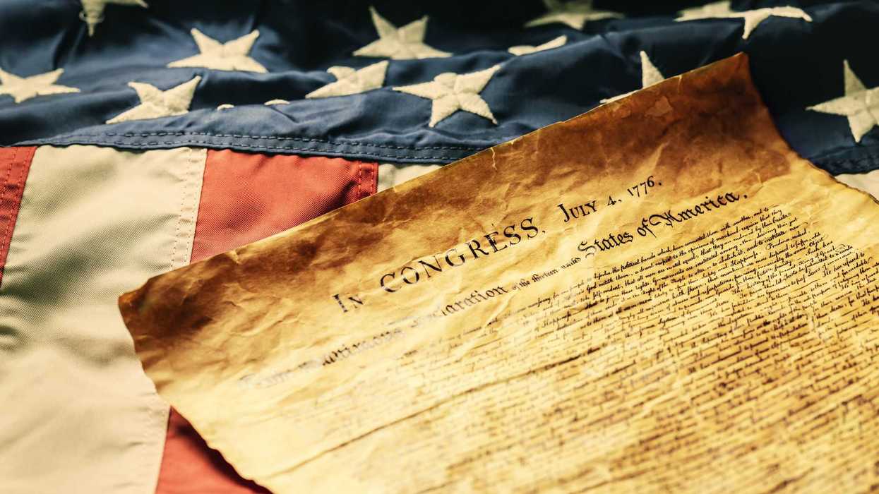 The Declaration of Independence of July 4, 1776, lies symbolically spread out on the American flag