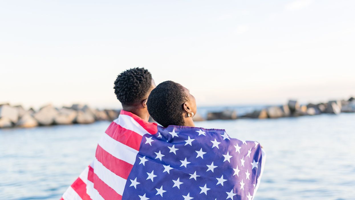 two Black people wrapped in an American flag