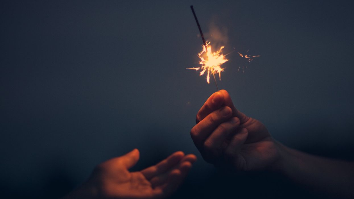 Two hands, people sharing a sparkler, fireworks.