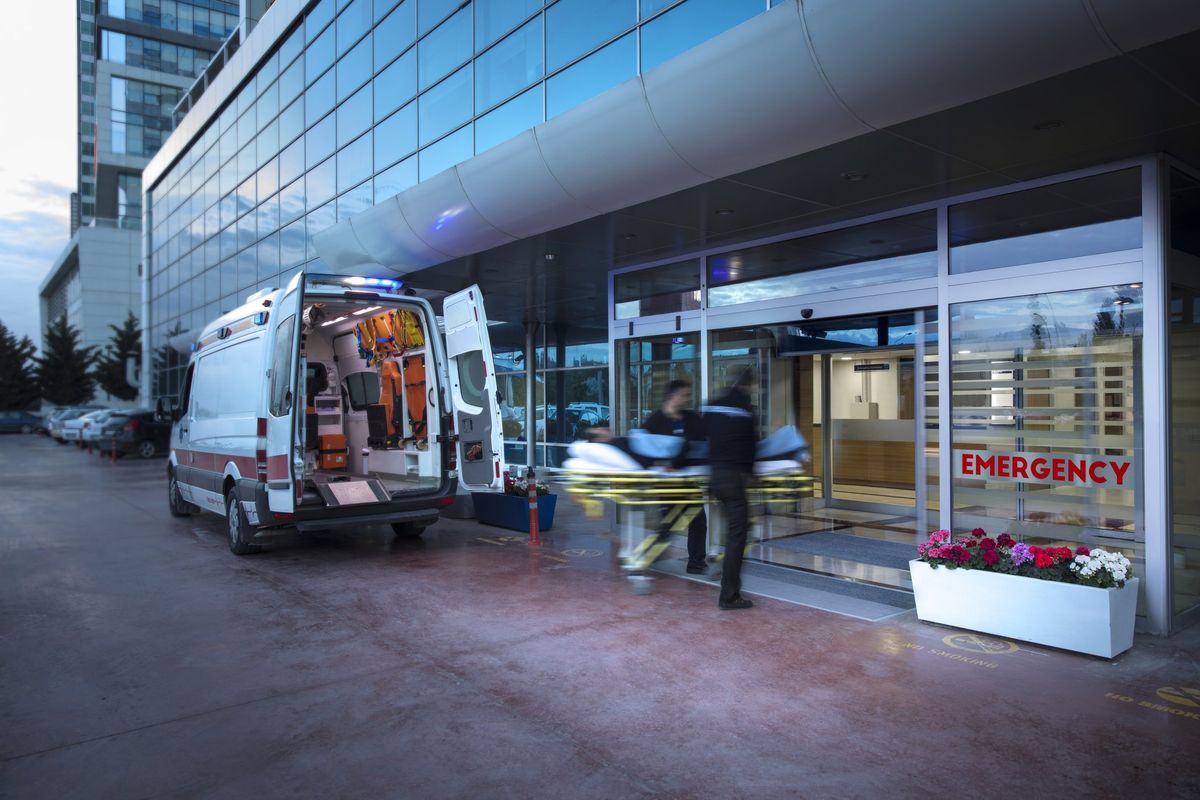 Two paramedics bringing in a person on a stretcher into a hospital.