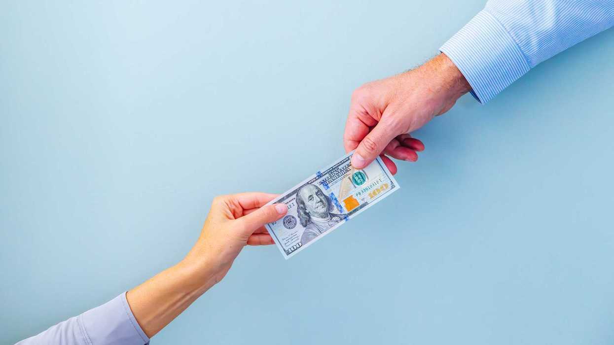 Two people, each holding one side of a $100 bill.