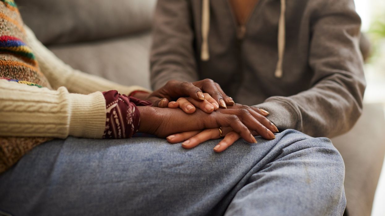 Two people holding hands, comforting each other.
