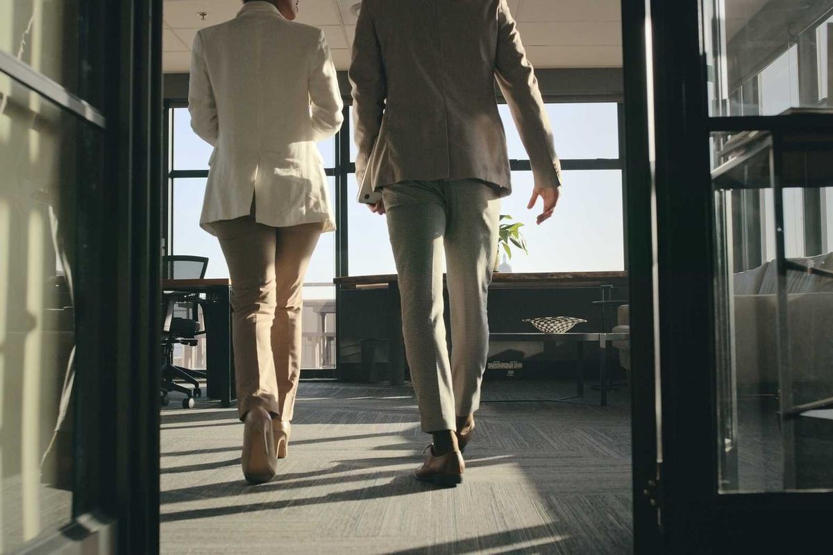 Two people in business attire walking into an office.