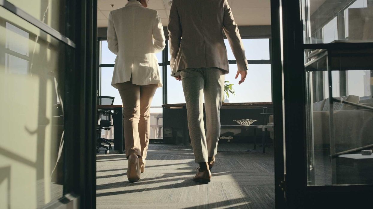 Two people in business attire walking into an office.