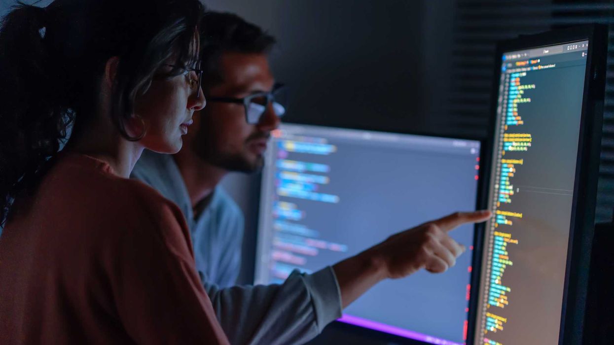 Two people looking at computer screens with data.