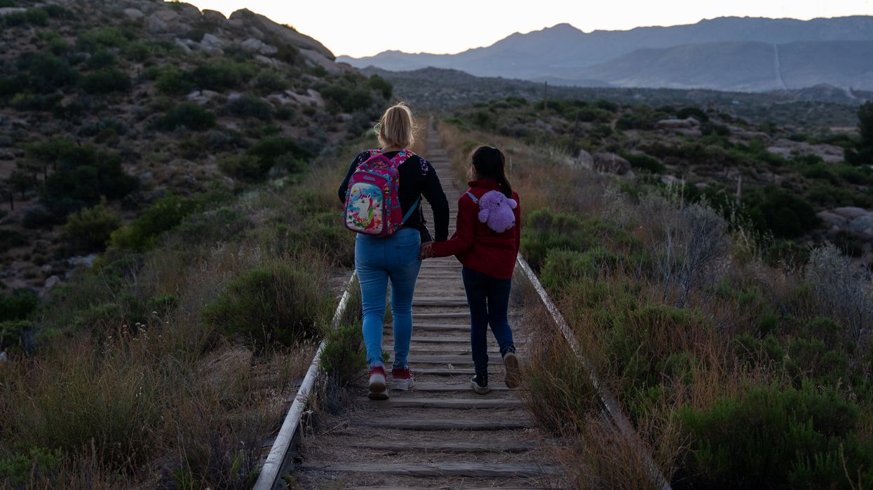 Two people walking along railroad tracks