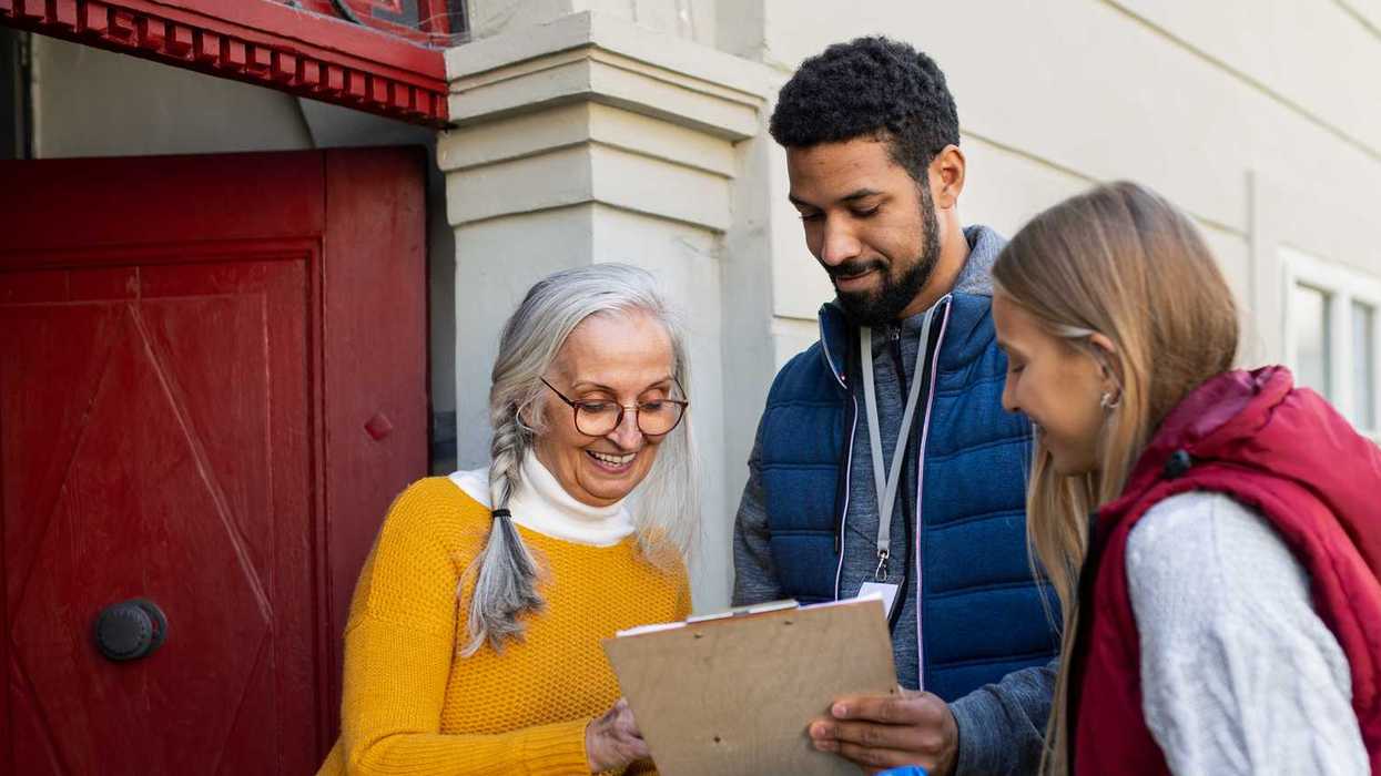 Two people with a clip board knocking on doors to speak with neighbors.