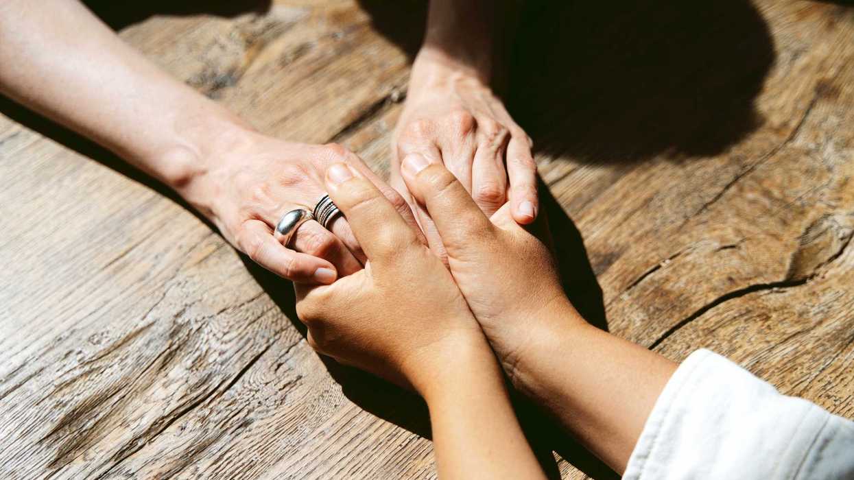 Two unrecognizable persons holding each other's hands