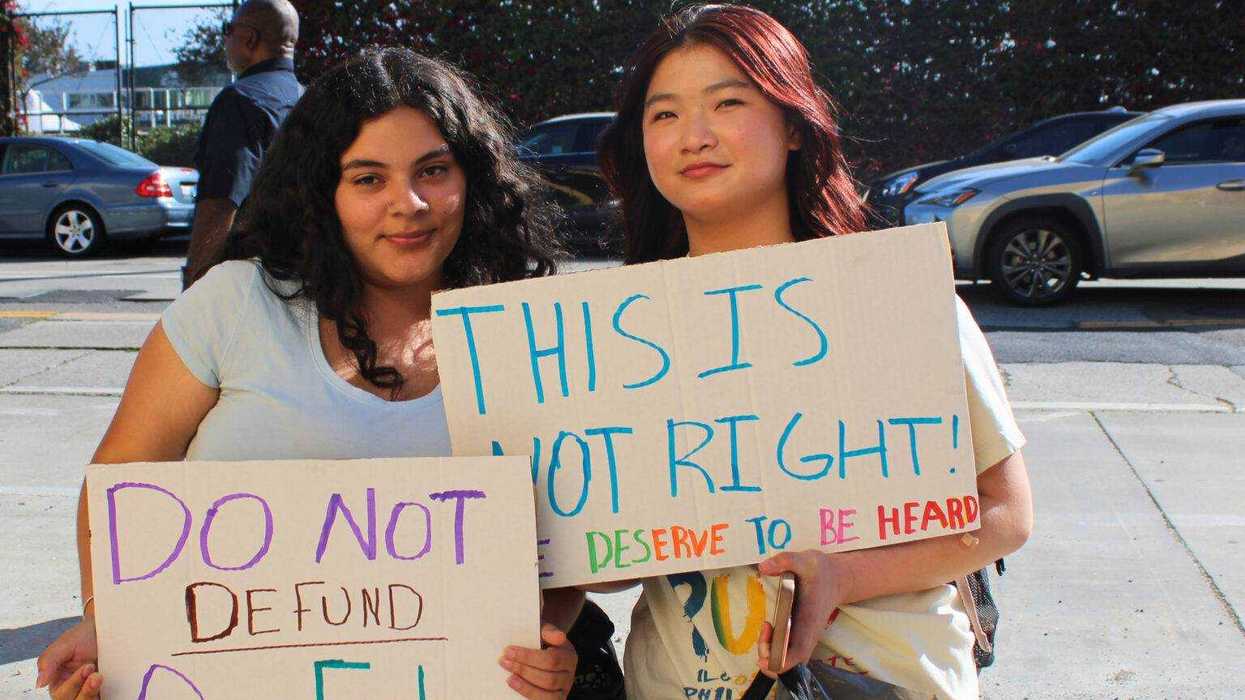 Two young people hold signs on education matters