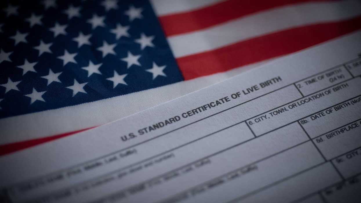 U.S. standard certificate of live birth application form next to flag of USA.
