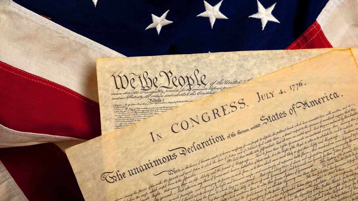 United States' Constitution and Declaration of Independence on a flag background