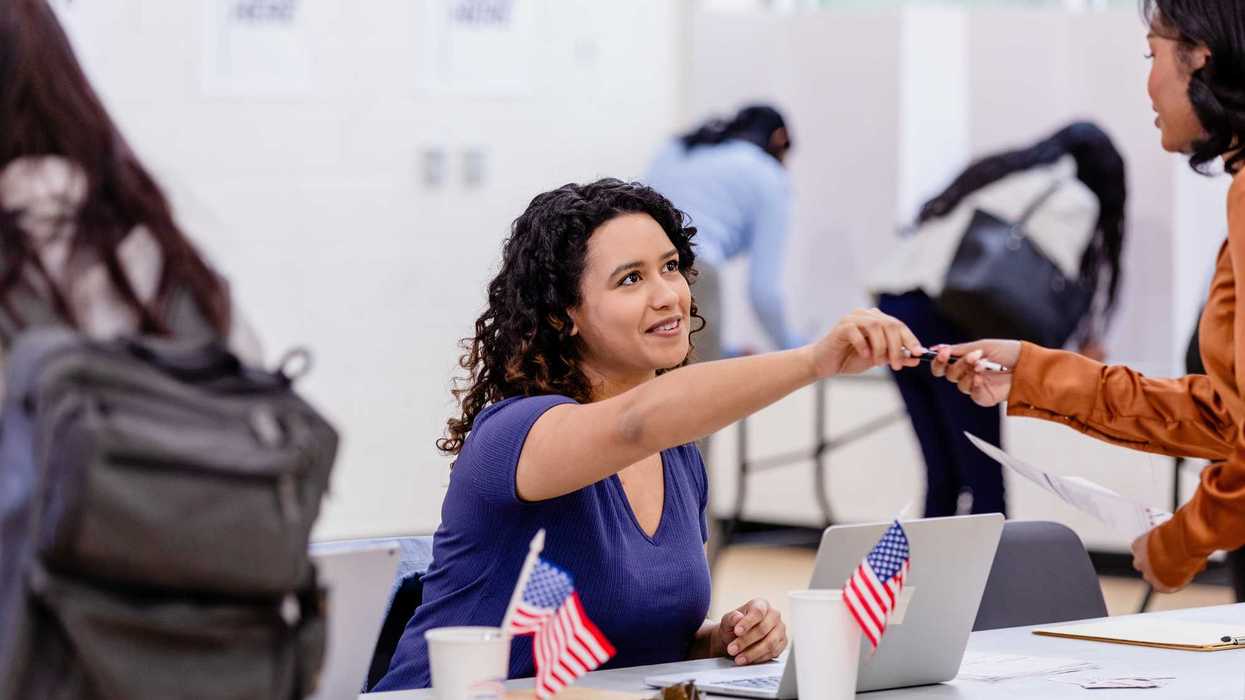 Voter receives a pen from poll worker at polling station.