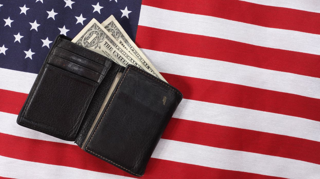wallet with dollar bills, on top of an American flag