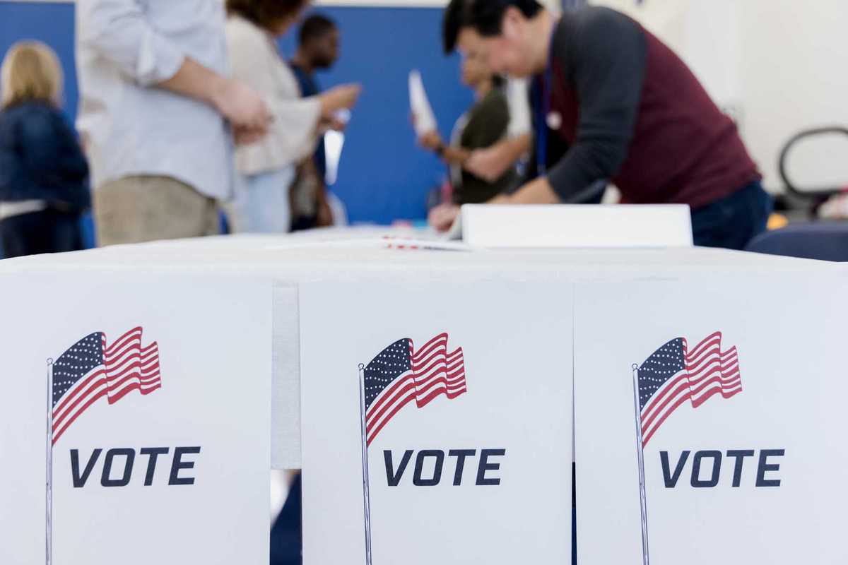 With the focus on the voting posters, the people in the background of the photo sign up to vote.