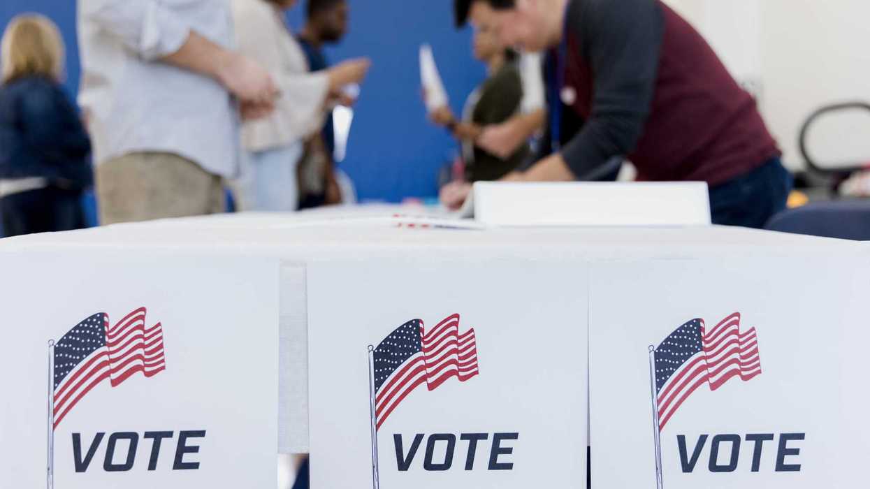 With the focus on the voting posters, the people in the background of the photo sign up to vote.