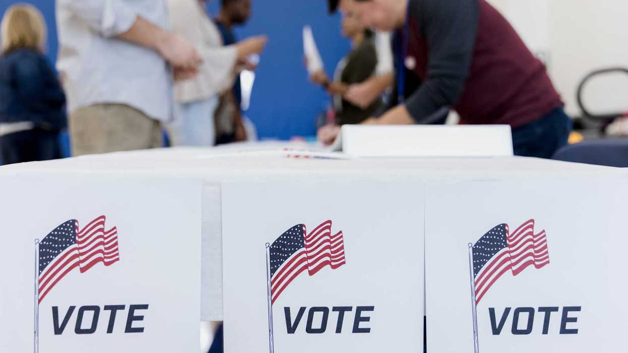 With the focus on the voting posters, the people in the background of the photo sign up to vote.