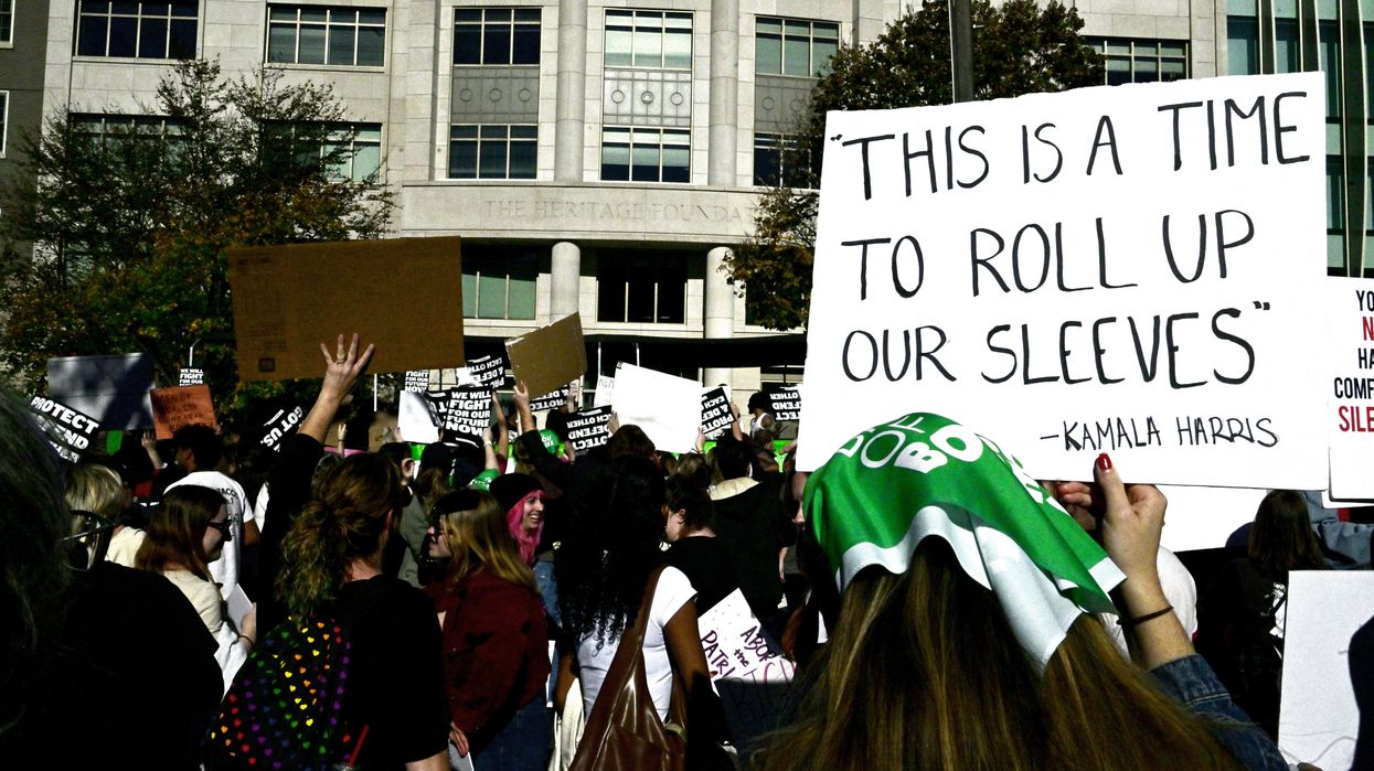 Woman holding a sign that reads "This is a time to roll up our sleeves."