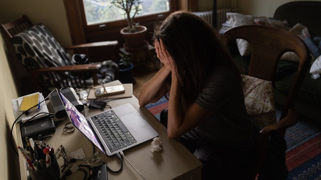 Woman holding her head in her hands in front of her computer