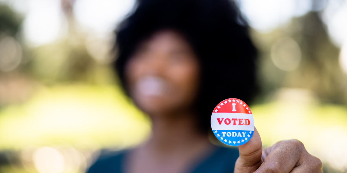 woman holds i voted sticker