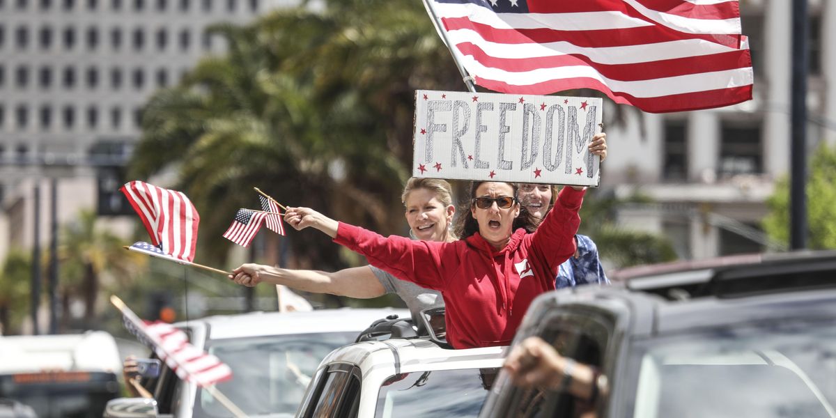 Woman holidng a sign that says "freedom" during a rally.