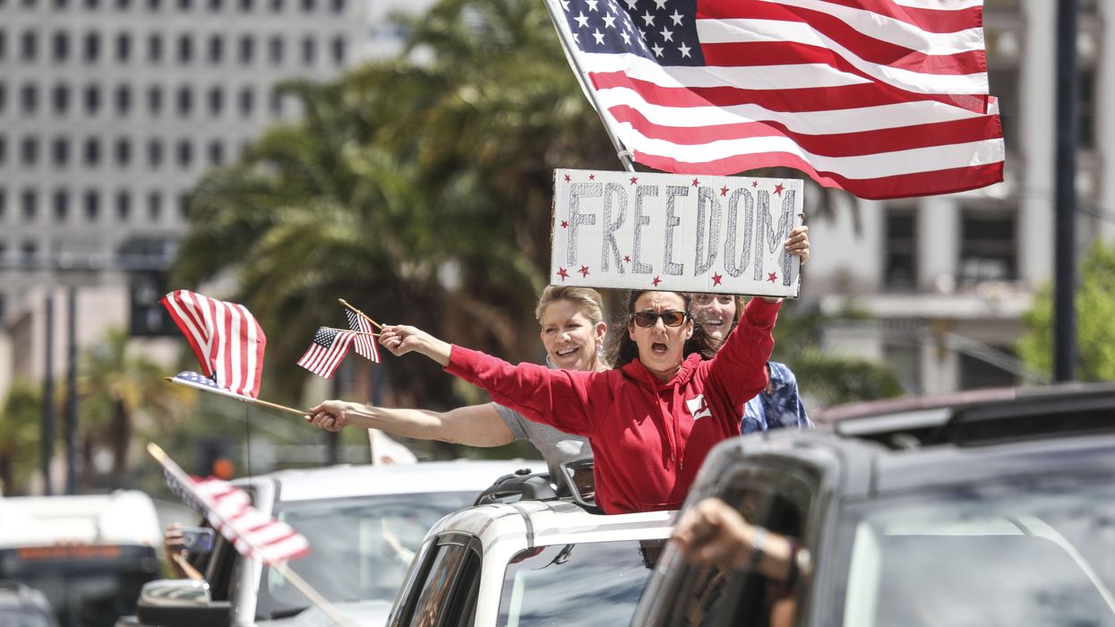 Woman holidng a sign that says "freedom" during a rally.