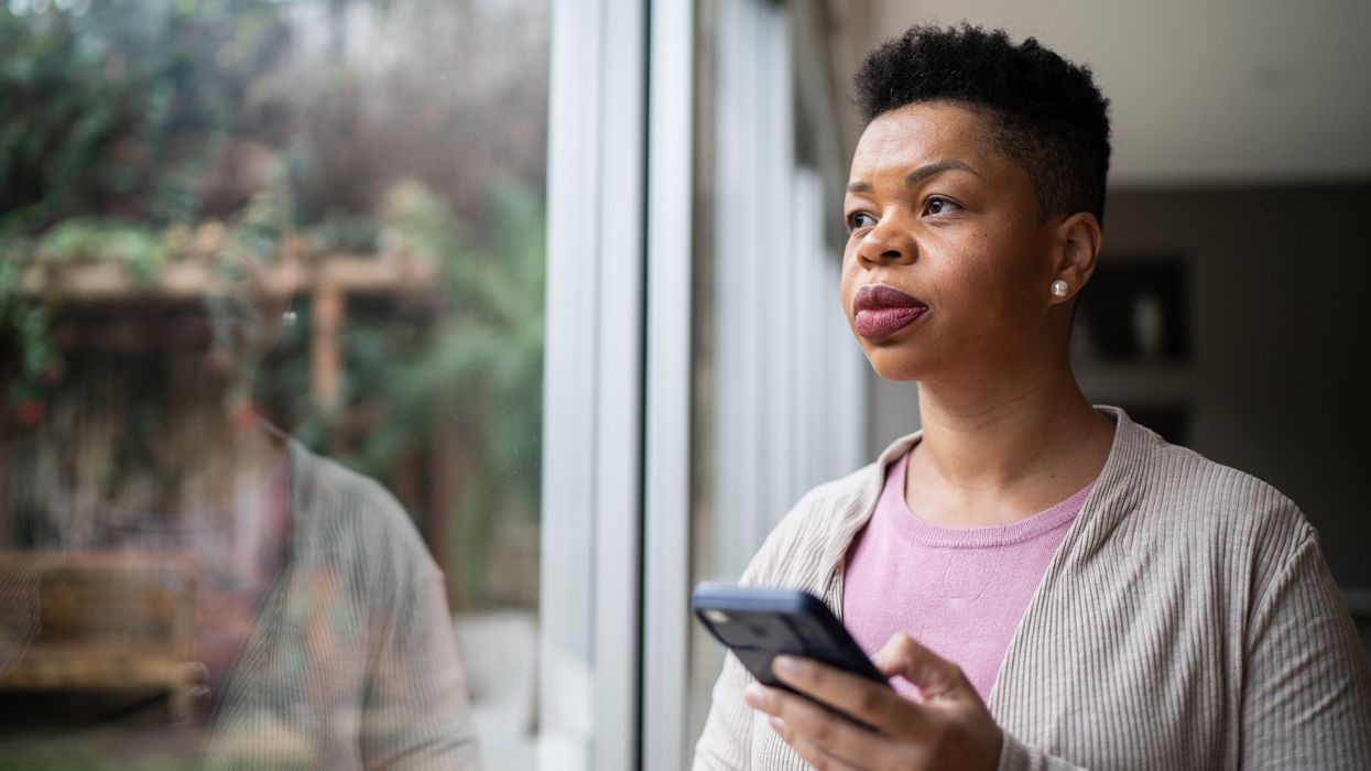 Woman looking off into the distance while holding her mobile phone