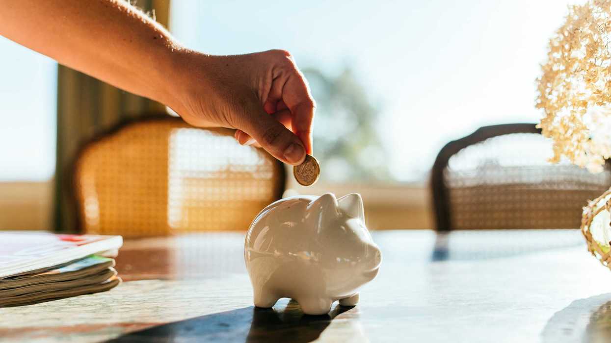 Woman putting savings in a white piggy bank.