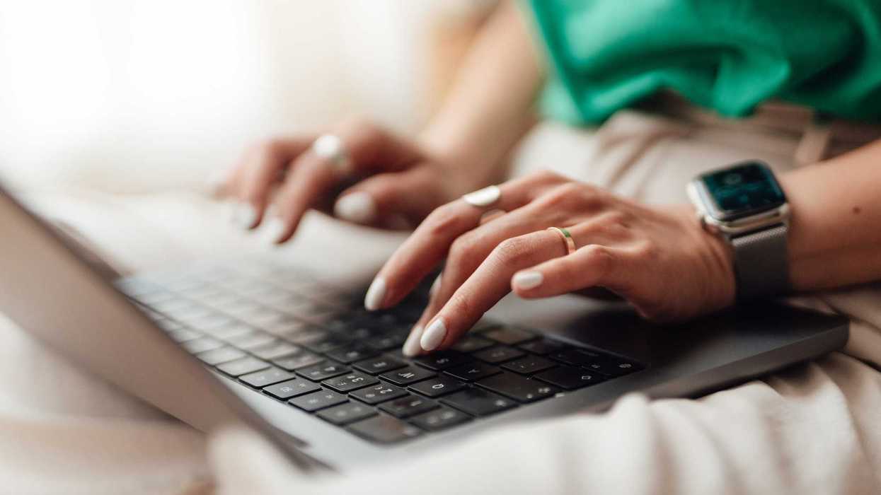 Woman sitting and typing on laptop on her lap.