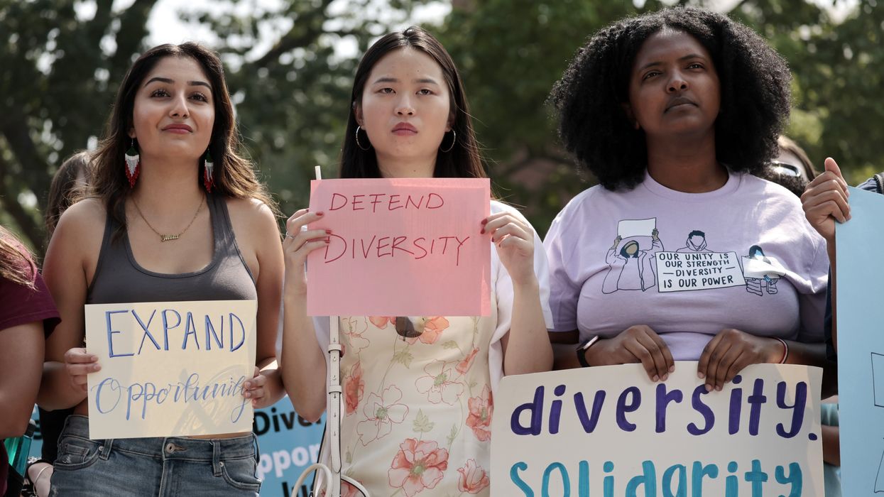 Women holding signs to defend diversity at Havard