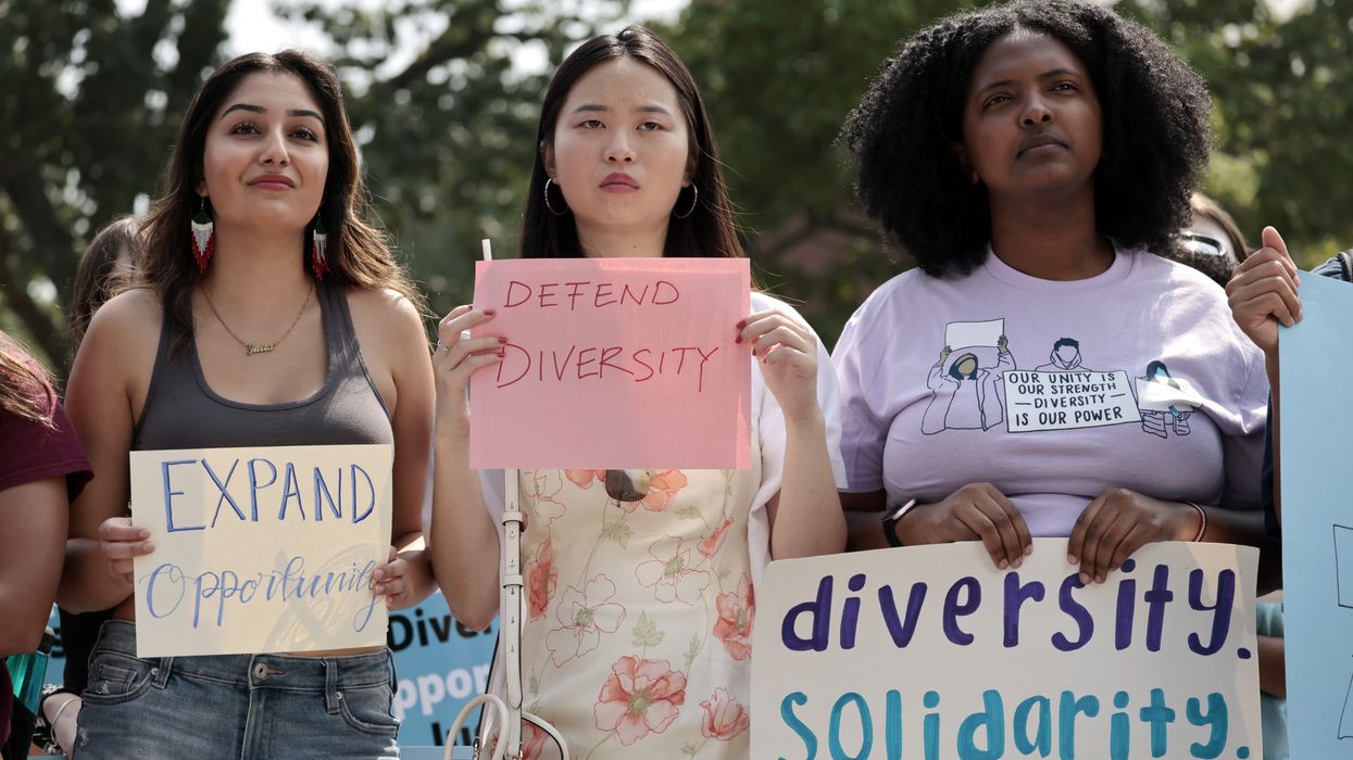 Women holding signs to defend diversity at Havard