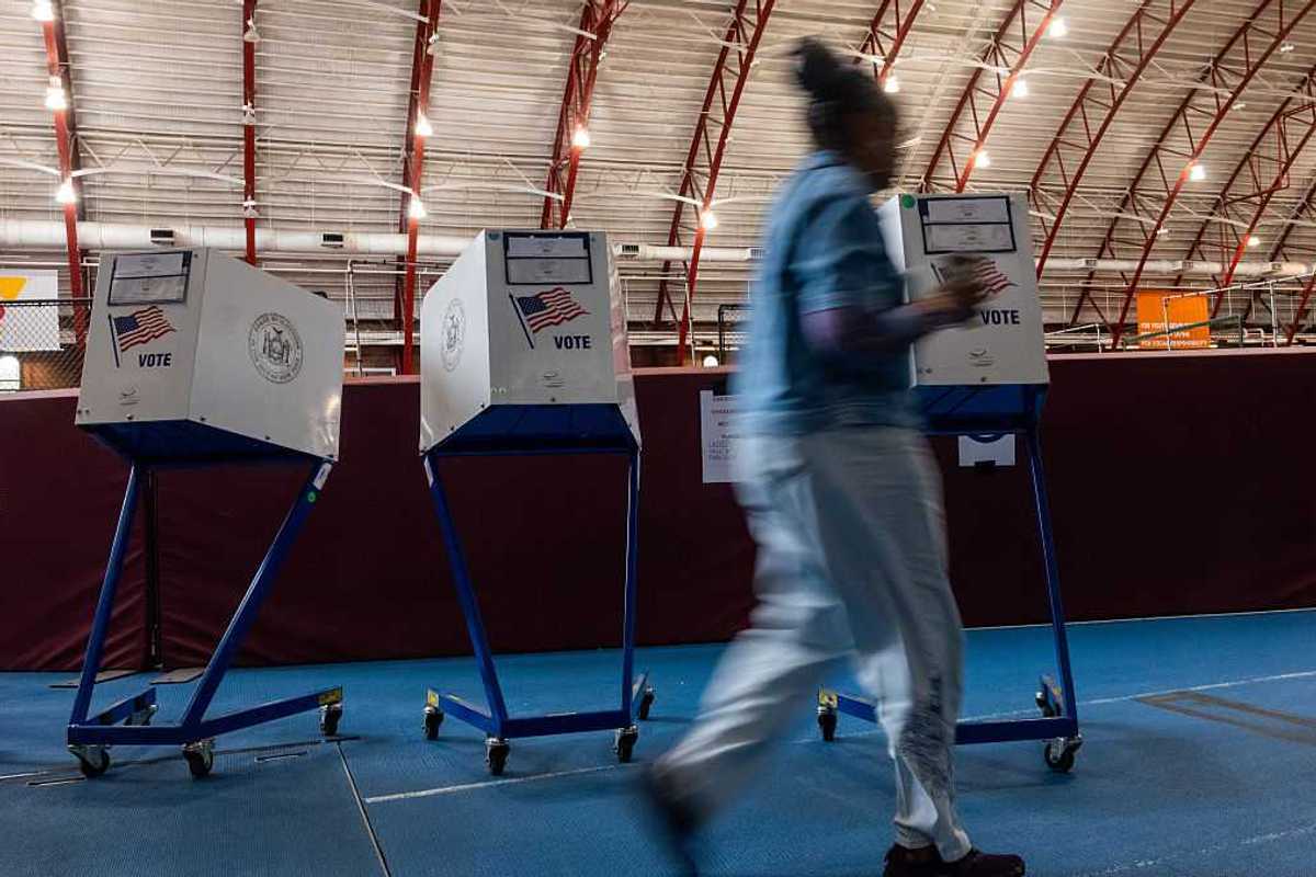 Women walks by voting booths.
