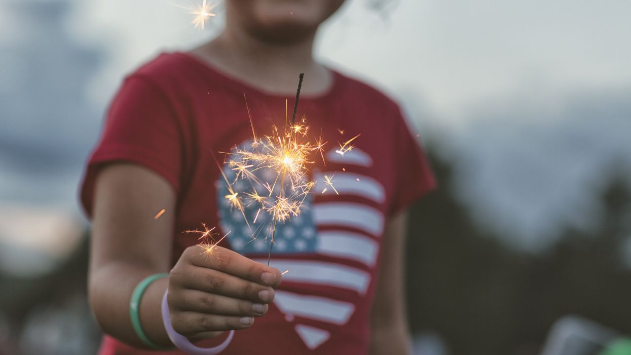 Young girl holding a sparkler and wearing an American flag shirt
