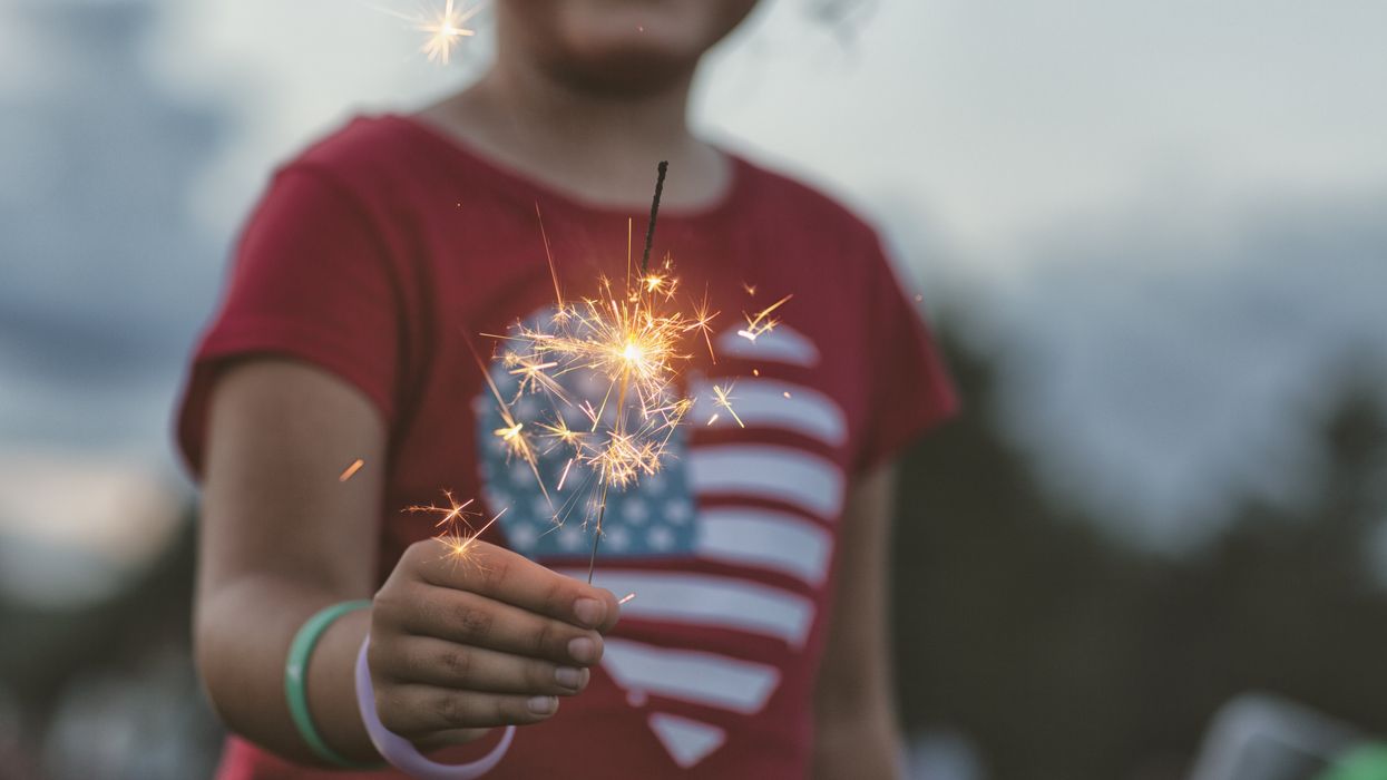 Young girl holding a sparkler and wearing an American flag shirt