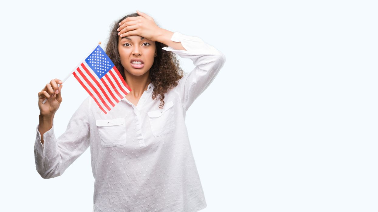 Young Hispanic woman holding a U.S. flag and looking stressed