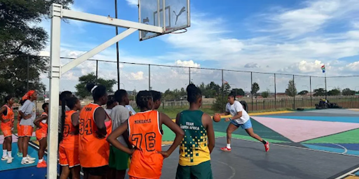 Youth watching a woman demonstrate basketball skills