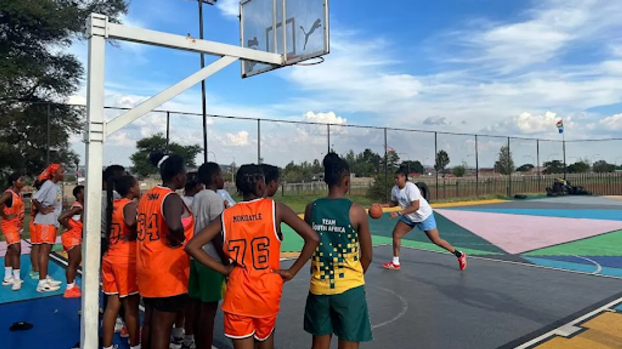 Youth watching a woman demonstrate basketball skills